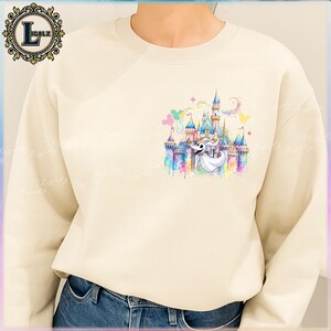 Puede incluir: Sudadera de color crema con un dise&ntilde;o de acuarela colorido de un castillo y un personaje fantasmal. El dise&ntilde;o incluye arco&iacute;ris pastel, estrellas y globos con forma de Mickey Mouse. La sudadera tiene cuello redondo y mangas largas.