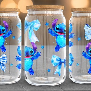 Puede incluir: Tres frascos de vidrio transparente con tapas de madera. Cada frasco presenta un personaje de dibujos animados azul, lazos azules y estrellas azules. El personaje tiene ojos grandes y est&aacute; en una pose juguetona. Los frascos est&aacute;n sobre una superficie gris.