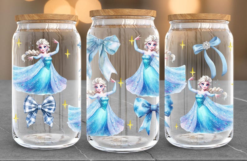 Puede incluir: Tres frascos de vidrio con tapas de madera, decorados con ilustraciones de una princesa con un vestido azul, lazos y estrellas doradas. Los frascos son transparentes y la princesa est&aacute; en una pose de baile.