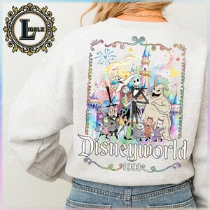 Puede incluir: Sudadera gris claro con un gr&aacute;fico colorido de personajes de The Nightmare Before Christmas frente a un castillo de Disney. La palabra "Disneyworld" est&aacute; escrita en una fuente decorativa, con "1993" debajo.