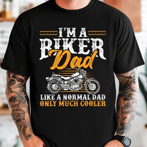 Puede incluir: Camiseta negra con un gr&aacute;fico de motocicleta y el texto "I'm a Biker Dad Like a normal dad only much cooler".