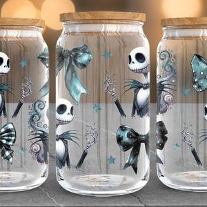Puede incluir: Tres frascos de vidrio con tapas de madera, decorados con un dise&ntilde;o de Jack Skellington. Cada frasco presenta un lazo, estrellas y la imagen de Jack. Los frascos son transparentes.