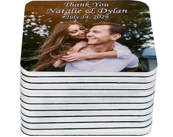 May include: Stack of square coasters. The top coaster features a photo of a smiling couple with the text "Thank You Natalie & Dylan July 14, 2029". The coasters have a white top and black edges.