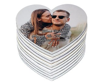 May include: A stack of heart-shaped coasters featuring a photograph of a couple. The photo shows a woman kissing a man on the cheek. The coasters have the text "Thank You Sarah & Anthony September 1, 2029".