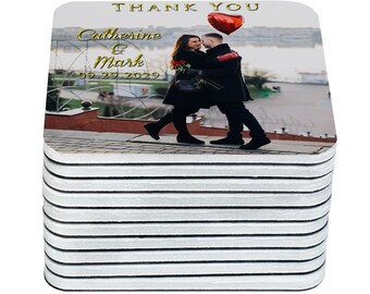 May include: A stack of square coasters with a wedding photo. The coasters feature a photo of a couple embracing, with the text "Thank You", and the names "Catherine & Mark" with the date "09.29.2029" in gold lettering.