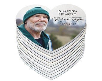 May include: A stack of heart-shaped memorial coasters with a photo of a man wearing a green hat. The text on the coaster reads "In loving memory Richard Taylor 1958-2023".