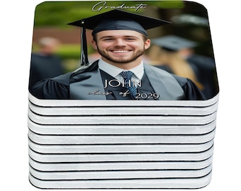 May include: A stack of square coasters featuring a graduation photo of a smiling person in a cap and gown. The text "Graduate", "JOHN", and "class of 2029" are visible on the coaster.