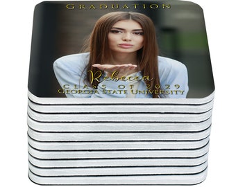 May include: A stack of square coasters featuring a graduation theme. The top coaster displays a photo of a woman blowing a kiss, with the text "Graduation," "Rebecca," "Class of 2029," and "Georgia State University" in gold lettering.