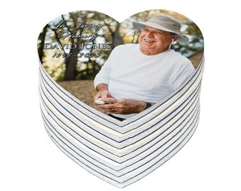 May include: A stack of white heart-shaped coasters with a photo of a man wearing a hat and smiling. The text on the coaster reads "In Loving Memory DAVID JONES 1978-2023".