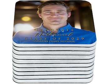 May include: A stack of white coasters with a photo of a graduate on the top coaster. The photo shows a young man smiling and wearing a blue shirt. The text on the coaster reads "Graduate Nathaniel Class of 2029 Collins High School".