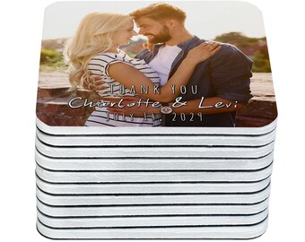 May include: A stack of square coasters featuring a photograph of a couple embracing, with the text "THANK YOU Charlotte & Levi JULY 14, 2029" in a script font. The coasters have a white border and a glossy finish.