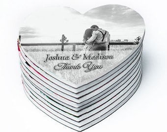 May include: A stack of heart-shaped wedding favors with a black and white photo of a couple. The text "Joshua & Madison Thank You" is printed on the front of the favors.