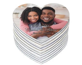 May include: Heart-shaped wedding favor featuring a photograph of a smiling couple. The photo is framed by a stack of coasters with a striped pattern in shades of gray and white. The text "Thank You Crystal & Devon June 23, 2020" is printed on the photo.