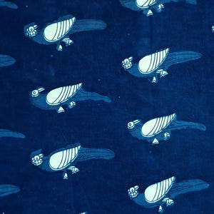 May include: A rectangular piece of dark blue fabric featuring a repeating pattern of stylised birds in a lighter blue shade. Each bird is depicted in profile with a distinct wing design and a small head, arranged in a consistent grid across the textile.