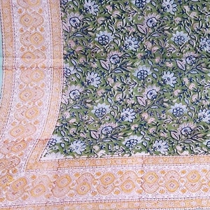May include: A green cotton bedspread with a floral print and a border of yellow and orange. The bedspread has a light blue border.