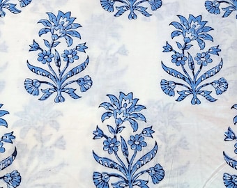 Pode incluir: Tecido de algodão branco com estampa floral azul. O tecido apresenta um padrão repetitivo de flores azuis estilizadas com detalhes intrincados.