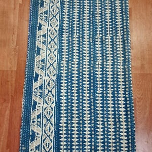 Puede incluir: Una colcha kantha azul y blanca con un patr&oacute;n geom&eacute;trico. La colcha tiene un borde blanco con un dise&ntilde;o floral.
