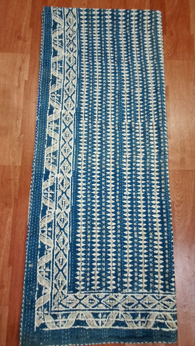 Puede incluir: Una colcha kantha azul y blanca con un patr&oacute;n geom&eacute;trico. La colcha tiene un borde blanco con un dise&ntilde;o floral.