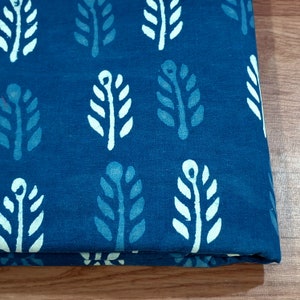 May include: A blue cotton fabric with a white leaf pattern. The fabric is folded in half and the pattern is visible on both sides.