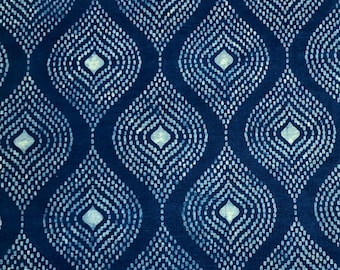 May include: A close-up of a fabric with a repeating pattern of dark blue teardrop shapes. Each teardrop is outlined with small white dots, and contains a white diamond shape in the center. The background is a solid dark blue.