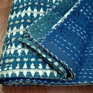 Puede incluir: Una colcha kantha azul y blanca con un patr&oacute;n geom&eacute;trico. La colcha est&aacute; doblada por la mitad y la tela es texturizada.