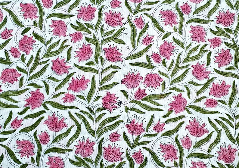 May include: White fabric with a repeating floral pattern. Pink flowers with green leaves and stems are printed across the surface. The design has a hand-drawn aesthetic, with the flowers and leaves outlined in a darker shade.