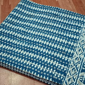 Puede incluir: Una tela de algod&oacute;n azul y blanco con un patr&oacute;n geom&eacute;trico. La tela tiene un borde con un dise&ntilde;o m&aacute;s intrincado.