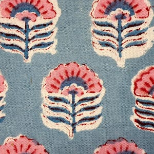 May include: Close-up of a blue fabric with a repeating floral pattern. The flowers are pink with blue and white accents, and the stems are blue. The fabric has a textured appearance.