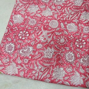 K&ouml;nnte beinhalten: Rosa Baumwollstoff mit wei&szlig;em Blumendruck. Der Stoff hat einen dezenten Batik-Effekt.