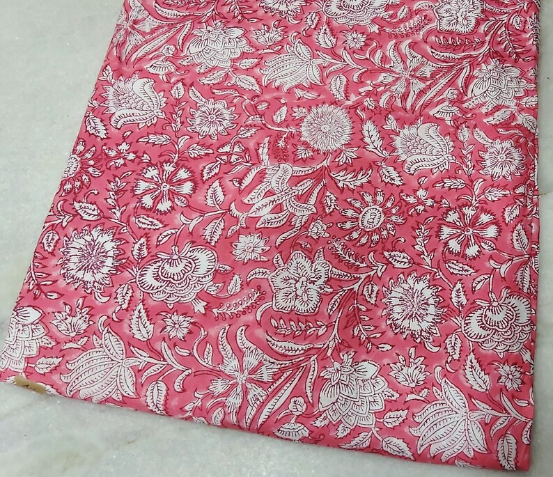 K&ouml;nnte beinhalten: Rosa Baumwollstoff mit wei&szlig;em Blumendruck. Der Stoff hat einen dezenten Batik-Effekt.