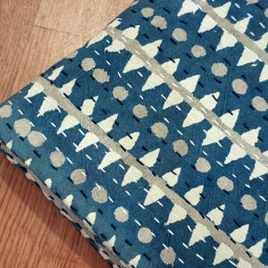 Puede incluir: Una colcha kantha azul y blanca con un patr&oacute;n geom&eacute;trico de tri&aacute;ngulos y c&iacute;rculos. La colcha est&aacute; hecha de algod&oacute;n y tiene un dise&ntilde;o cosido a mano.