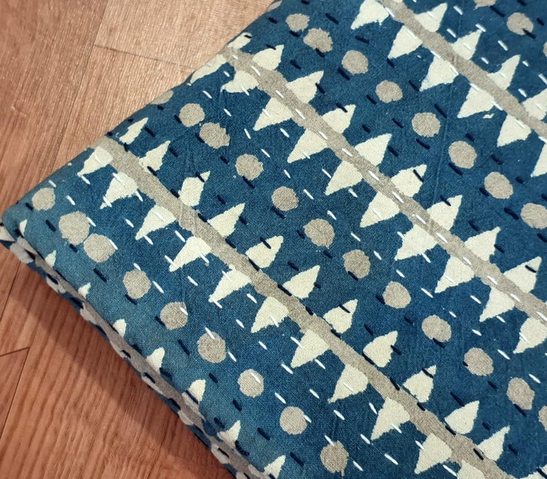 Puede incluir: Una colcha kantha azul y blanca con un patr&oacute;n geom&eacute;trico de tri&aacute;ngulos y c&iacute;rculos. La colcha est&aacute; hecha de algod&oacute;n y tiene un dise&ntilde;o cosido a mano.