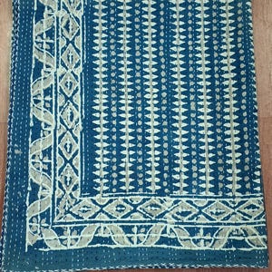 Puede incluir: Una colcha kantha azul y blanca con un patr&oacute;n geom&eacute;trico. La colcha tiene un borde blanco con un dise&ntilde;o floral.
