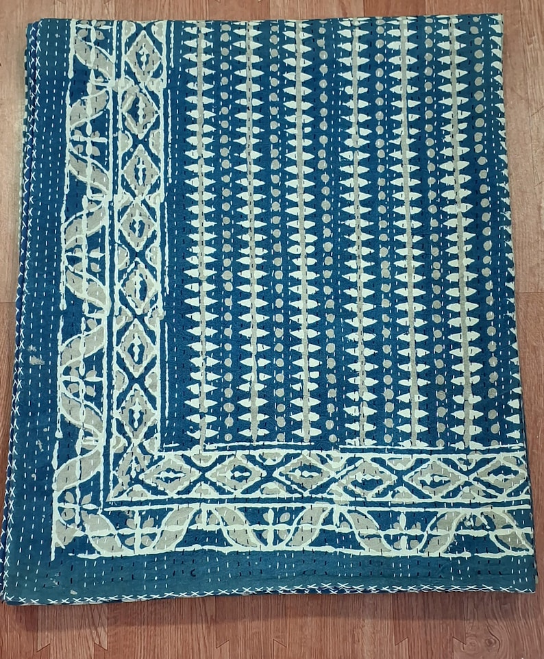 Puede incluir: Una colcha kantha azul y blanca con un patr&oacute;n geom&eacute;trico. La colcha tiene un borde blanco con un dise&ntilde;o floral.