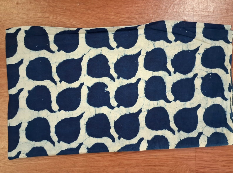 Puede incluir: Una tela blanca con un patr&oacute;n azul de formas de l&aacute;grima repetidas. La tela est&aacute; doblada por la mitad.