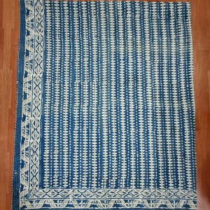 Puede incluir: Una colcha kantha azul y blanca con un patr&oacute;n geom&eacute;trico. La colcha tiene un borde blanco con un dise&ntilde;o repetitivo.