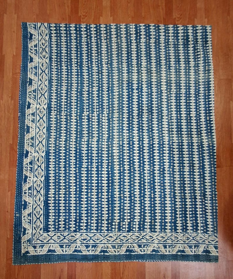 Puede incluir: Una colcha kantha azul y blanca con un patr&oacute;n geom&eacute;trico. La colcha tiene un borde blanco con un dise&ntilde;o repetitivo.