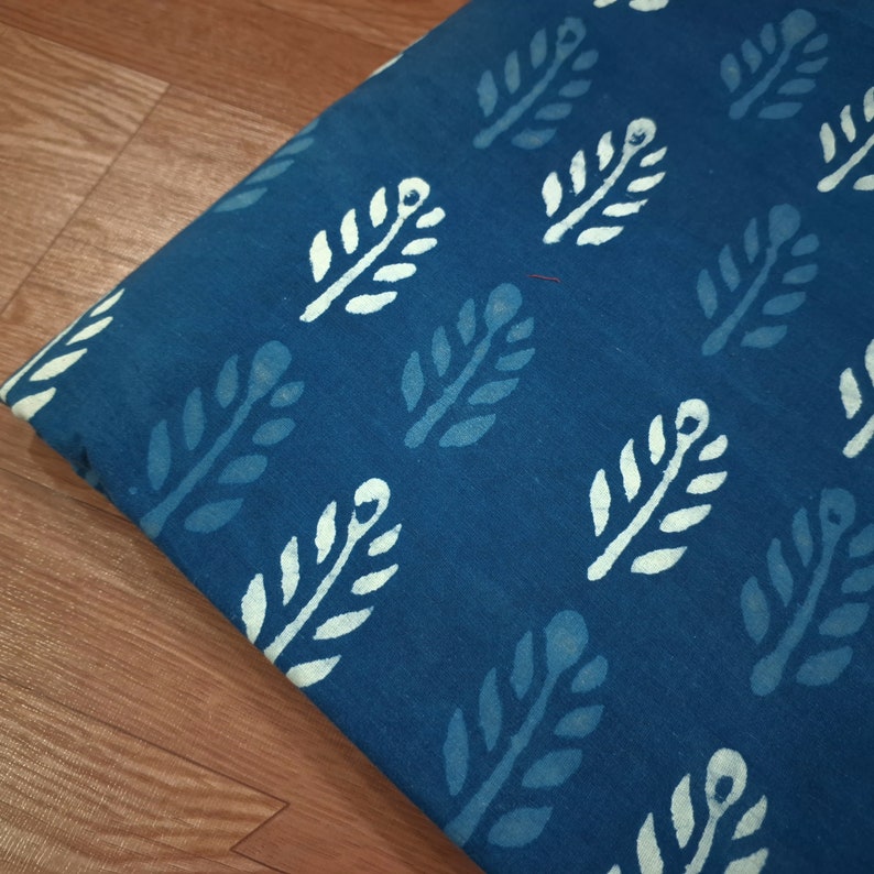 May include: Blue fabric with a white leaf pattern. The fabric has a textured, hand-woven look.
