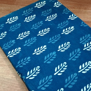 May include: A teal blue fabric with a white leaf pattern. The fabric is a cotton blend and is perfect for quilting, sewing, and crafting.