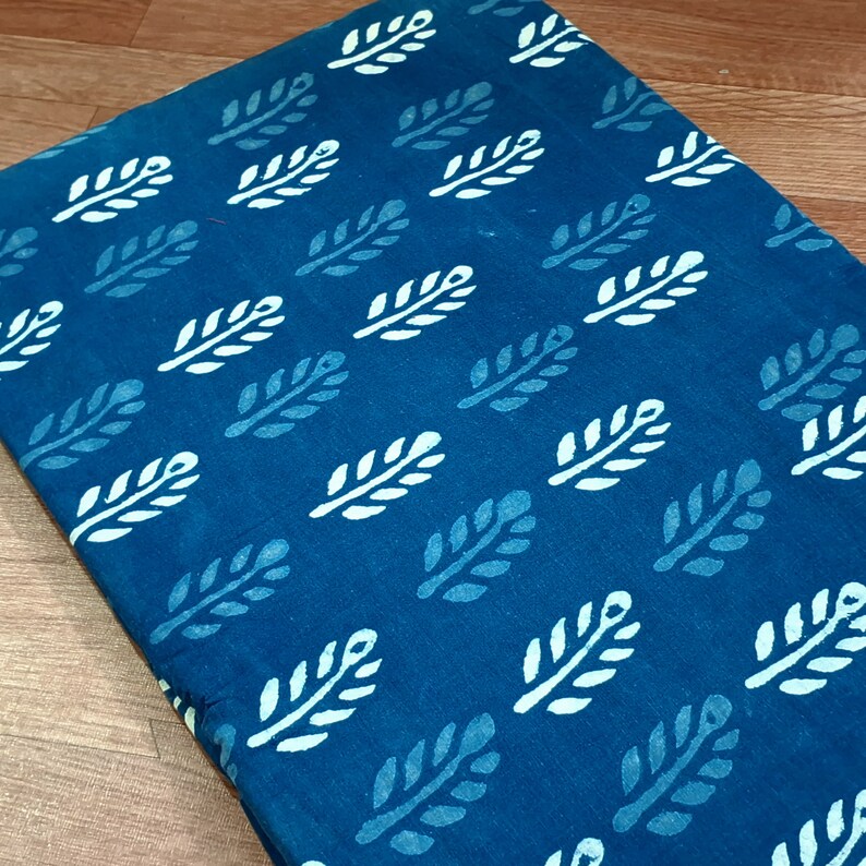 May include: A teal blue fabric with a white leaf pattern. The fabric is a cotton blend and is perfect for quilting, sewing, and crafting.