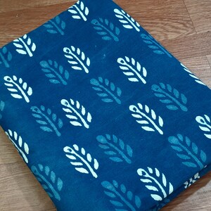May include: Blue cotton fabric with a white leaf pattern. The fabric is folded in half and has a textured surface.