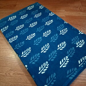 May include: A teal blue fabric with a white leaf pattern. The fabric is a cotton blend and is perfect for quilting, sewing, and crafting.