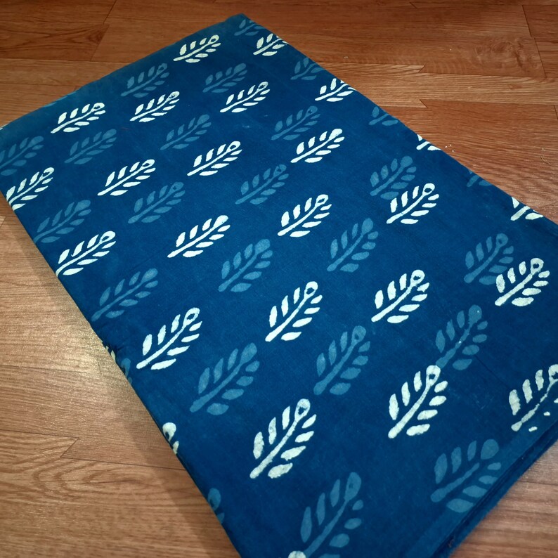 May include: A teal blue fabric with a white leaf pattern. The fabric is a cotton blend and is perfect for quilting, sewing, and crafting.
