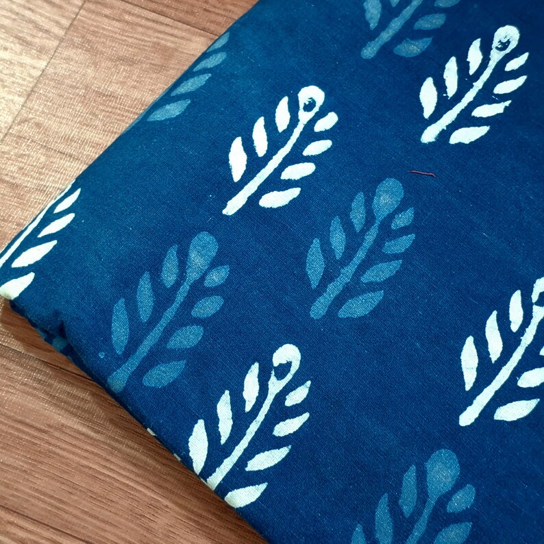 May include: A close-up of a blue fabric with a white leaf pattern. The fabric is a cotton blend and has a soft, textured feel.