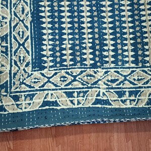 Puede incluir: Una colcha kantha azul y blanca con un patr&oacute;n geom&eacute;trico. La colcha est&aacute; cosida a mano y tiene un borde con flecos.