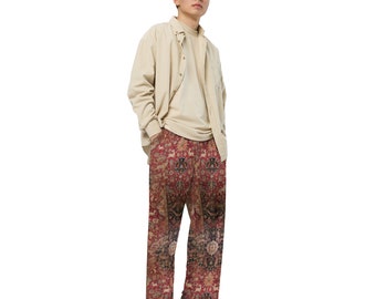 May include: A person wearing a beige button-down shirt and red patterned trousers. The trousers have a detailed design that resembles a rug.