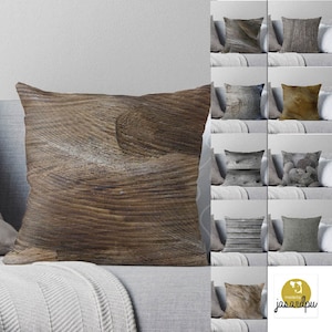 May include: A brown throw pillow with a wood grain pattern. The pillow is on a couch with a gray blanket. The pillow is made by jassandpu.