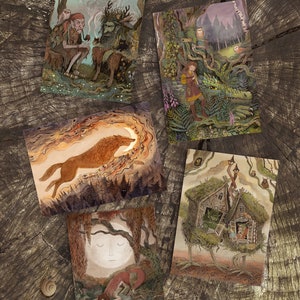 Op de afbeelding: Set van vijf geïllustreerde kaarten met fantasievolle bosscènes. De kaarten tonen een wolf die huilt naar de maan, een meisje met een draak, een huis op stelten, twee figuren in een bos en een vos aan een rivier.