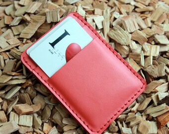 Può includere: Un porta carte in pelle rosa con un bordo cucito. Il porta carte ha una tasca per una carta con il testo "I Love You" e il numero 4149 stampato su di esso.