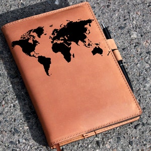 May include: A brown leather journal with a world map embossed on the front cover. A black pen is tucked into the journal's strap.